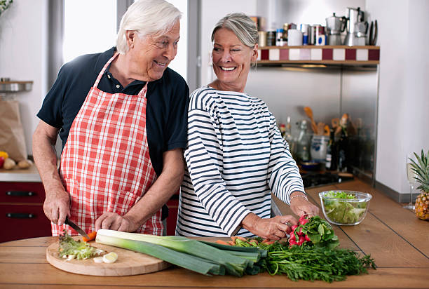 Couple de personnes âgées qui cuisine des légumes pour un repas sain