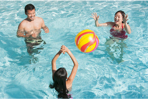 parents qui jouent au ballon avec leur enfant dans une piscine