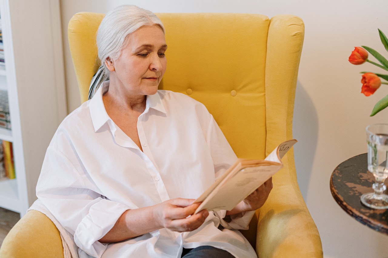 femme âgée assise dans un fauteuil jaune