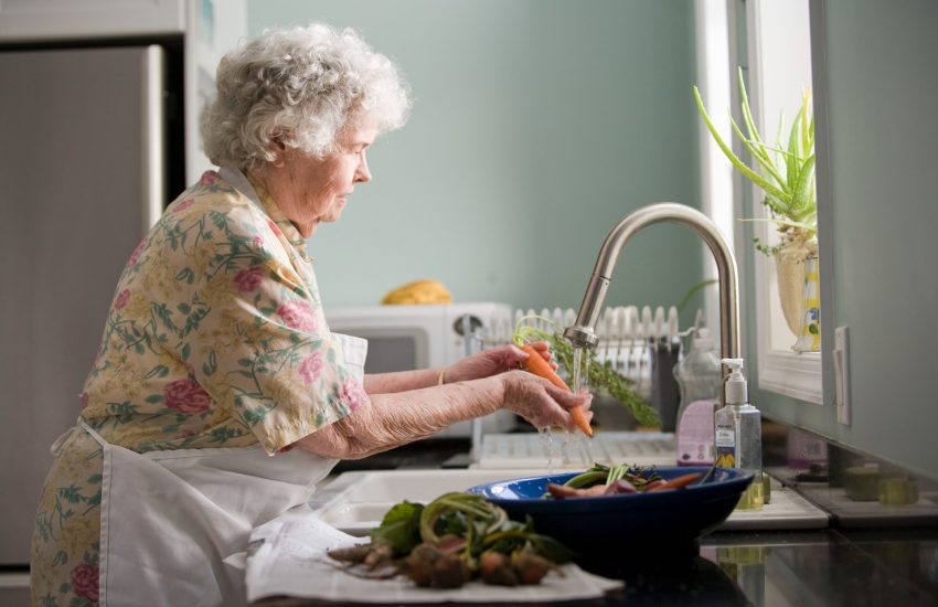 femme âgée lave des légumes